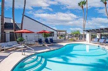 a pool with lounge chairs and umbrellas at the enclave at woodbridge apartments in sugar at Ascent on Pantano Apartments, Tucson, AZ