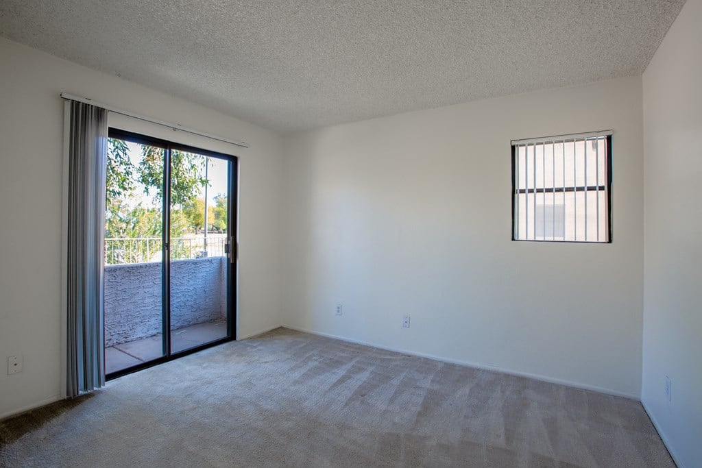 Empty room with a carpeted floor and a window with blinds.at Ascent on Spence, Tempe Arizona