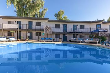 a resort style pool with lounge chairs and umbrellas