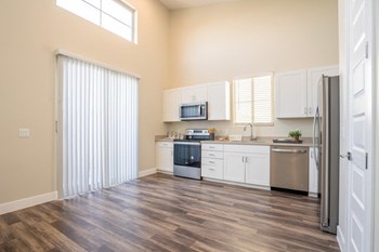 Model kitchen at Village Green of Queen Creek with wood-style flooring, modern appliances and a sliding glass door - Photo Gallery 2