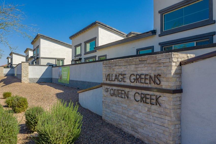 Landscaped wall along the property with a sign "Village Green of Queen Creek" - Photo Gallery 1