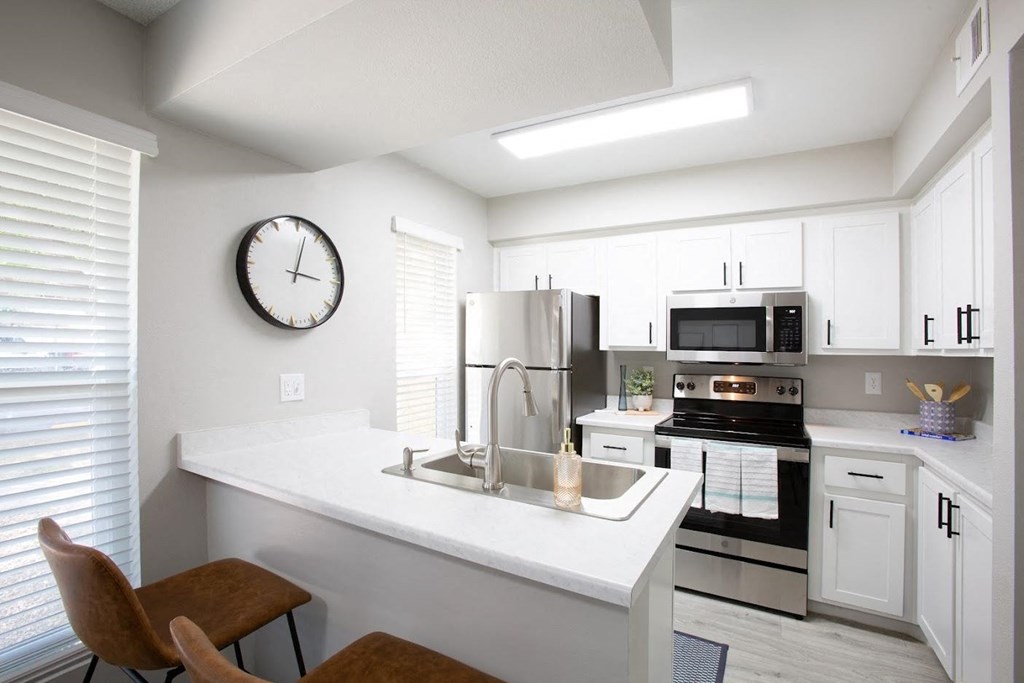 a kitchen with white cabinets and a large clock on the wall at Ascent on Peoria Apartments, Phoenix, AZ 85029