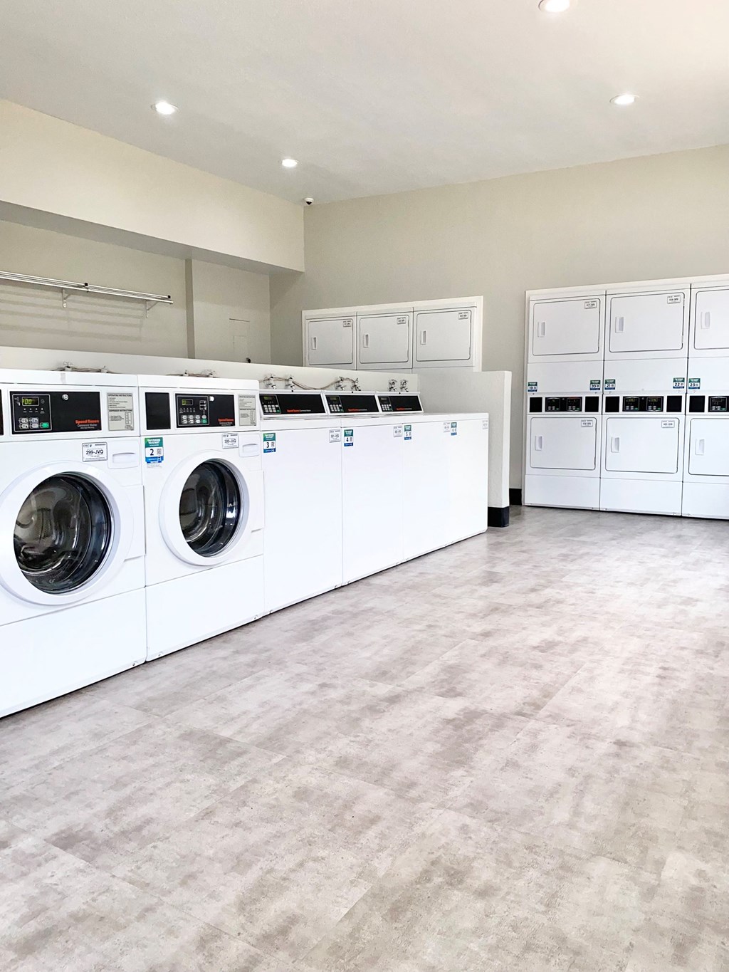 a large laundry room with white washers and dryers
