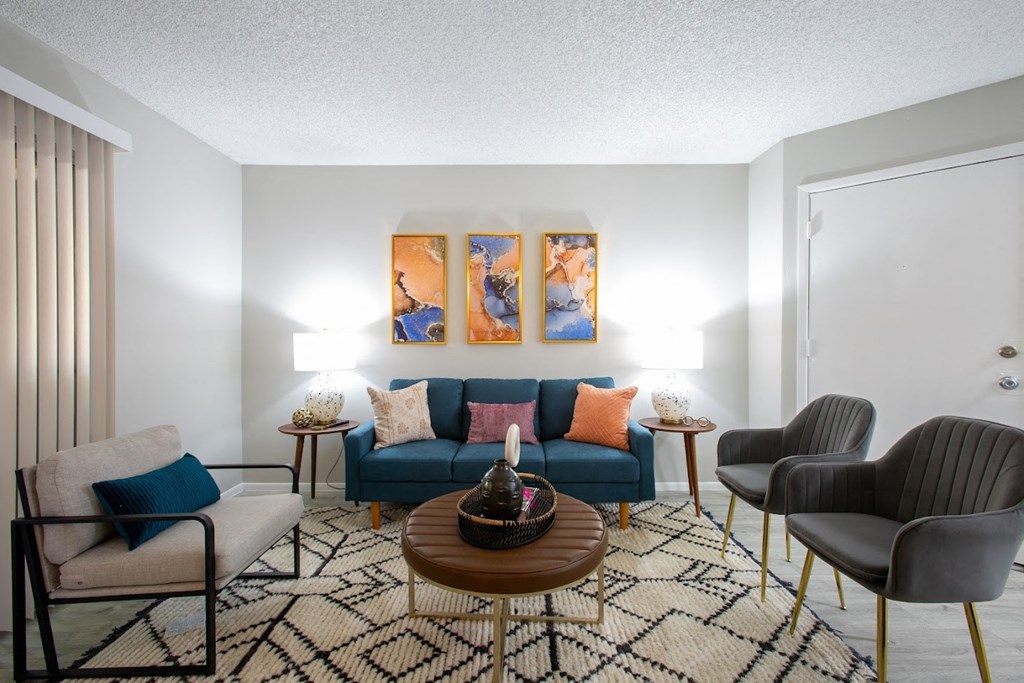 a living room with a blue couch and three chairs at Ascent on Peoria Apartments, Phoenix, Arizona