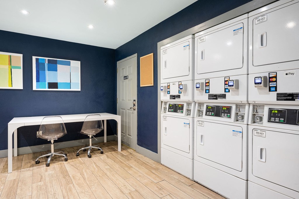 a laundry room with a table and chairs and a row of white washers and dryers at Nextloft Apartments, South Carolina, 29910