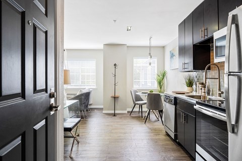 a kitchen with black cabinets and a dining room with a table and chairs