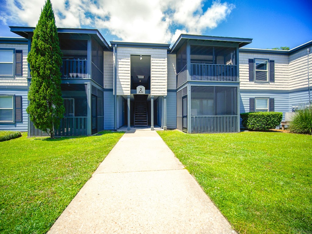 front view of an apartment building with a sidewalk and grass