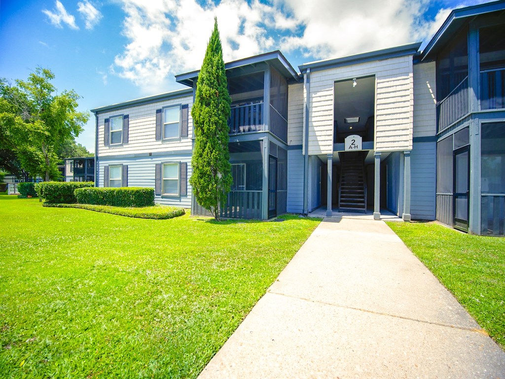 front view of an apartment building with a sidewalk and grass