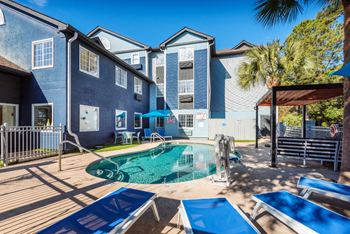 Apartment swimming pool with seating and umbrellas at NEXTLoft in Bluffton, SC. - Photo Gallery 4