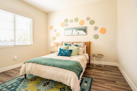 Model bedroom is furnished with a large bed and 2 nightstands at Village Greens of Queen Creek