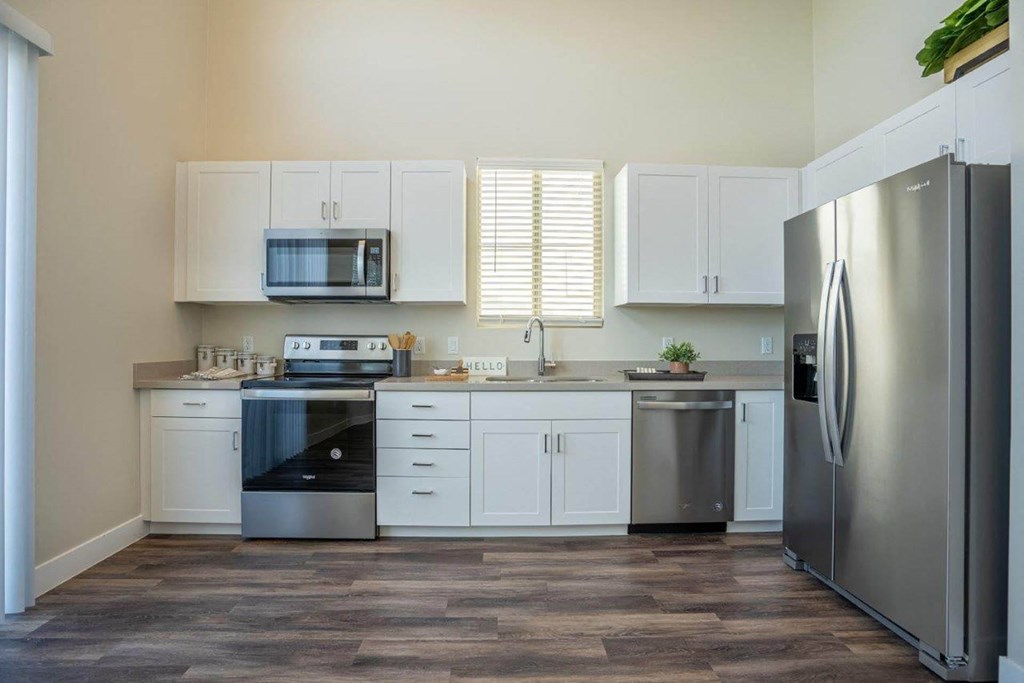 A kitchen with wood-style flooring and stainless steel appliances in an apartment at Village Greens of Queen Creek