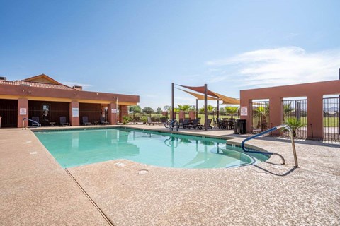The pool is surrounded by a sundeck with lounge chairs at Village Greens of Queen Creek