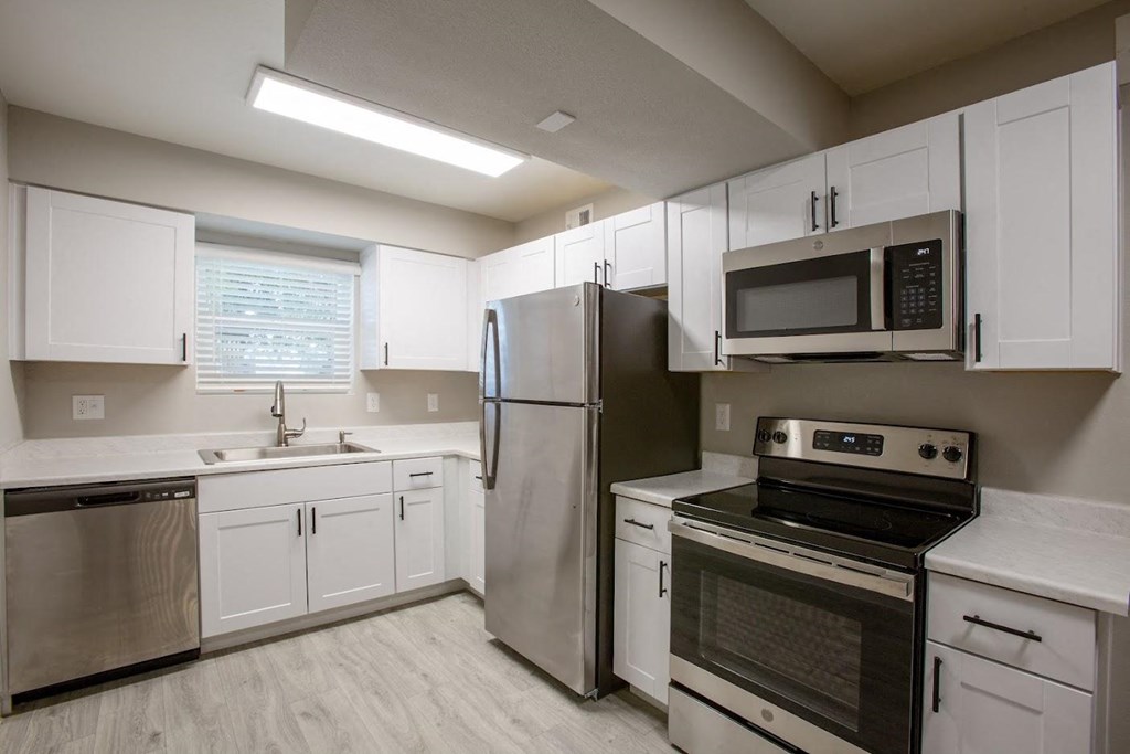 a kitchen with white cabinets and stainless steel appliances