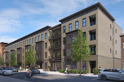 A street view of a modern apartment complex with cars parked on the side of the road.