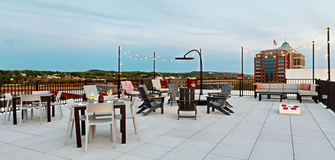 a rooftop patio with tables and chairs and a view of the city