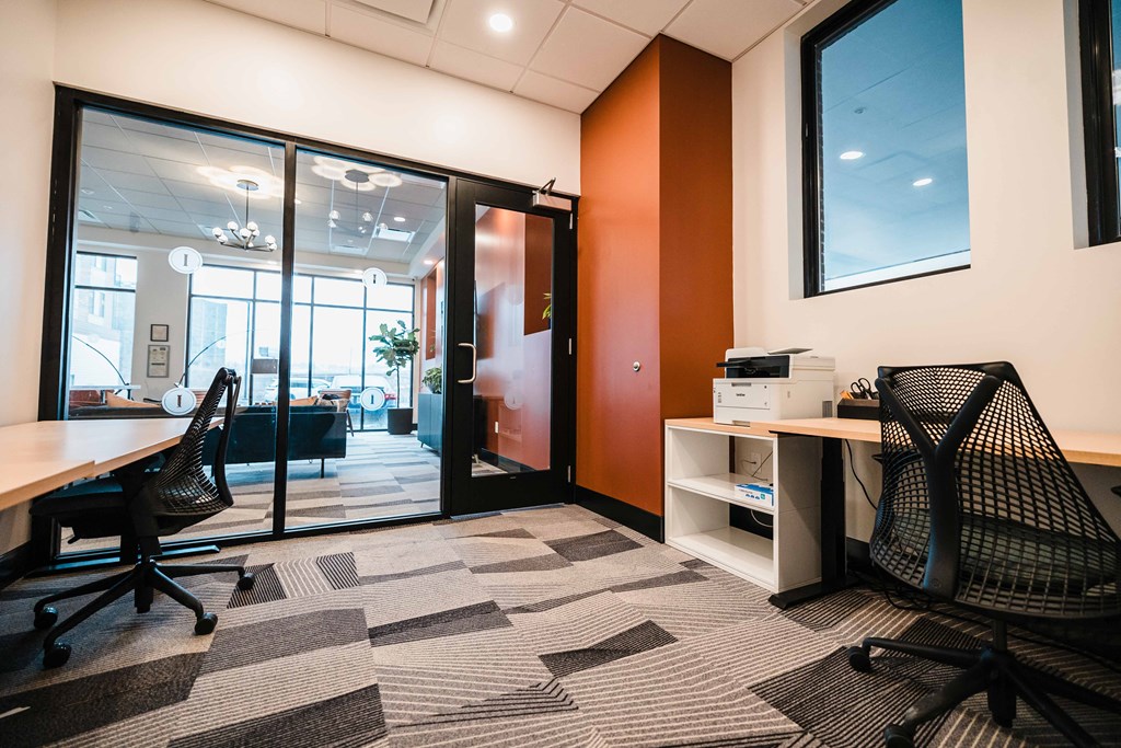 Resident coworking lounge with ergonomic chairs and powered sit-stand desks. at Industrie Apartments, Albany, NY