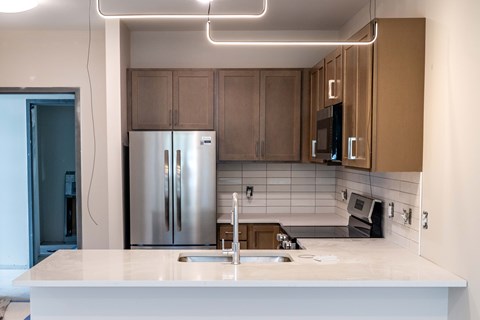 A modern kitchen with a white countertop and stainless steel appliances.