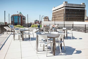 a rooftop patio with tables and chairs and a city in the background at Industrie Apartments, Albany