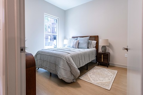 A bedroom with a bed, nightstand, and window.