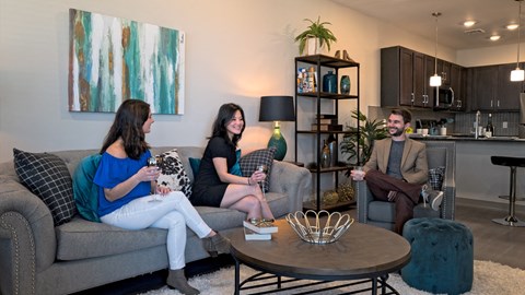 three people sitting on a couch in a living room