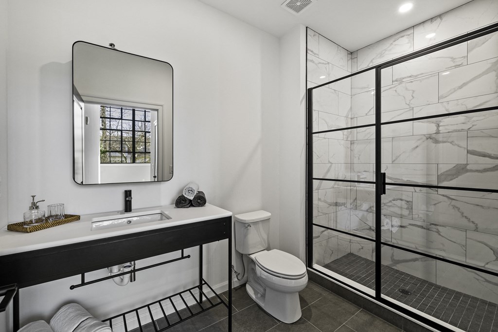 a bathroom with a shower toilet and sink and a mirror