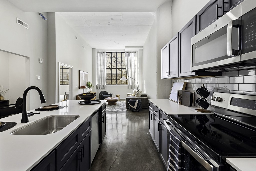 a kitchen with white counters and black appliances and a large window