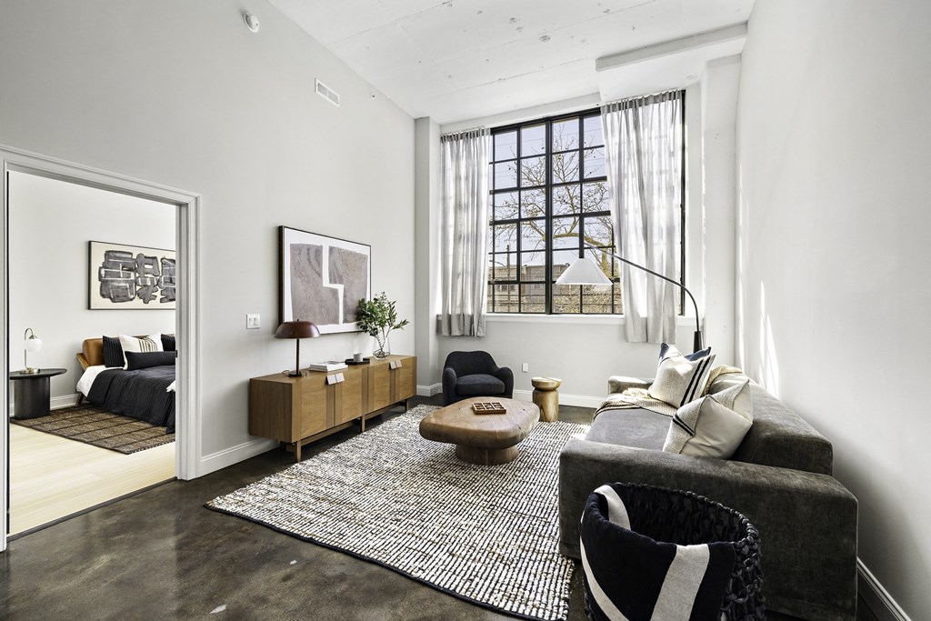 a living room with a gray couch and a rug and a window