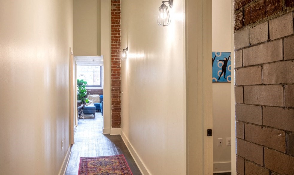 the hallway of a home with a brick wall and a carpet