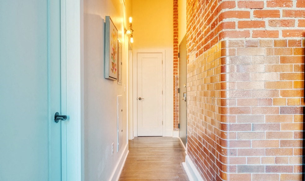 a hallway with a brick wall and a white door