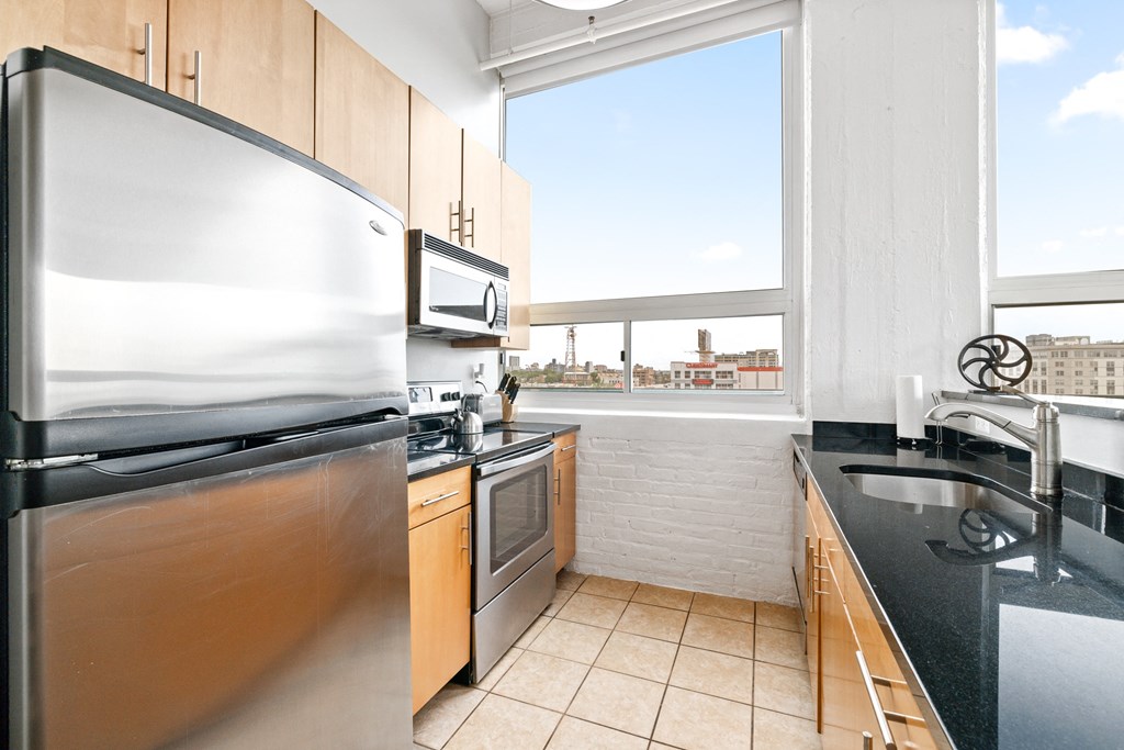 a kitchen with black countertops and stainless steel appliances and a large window