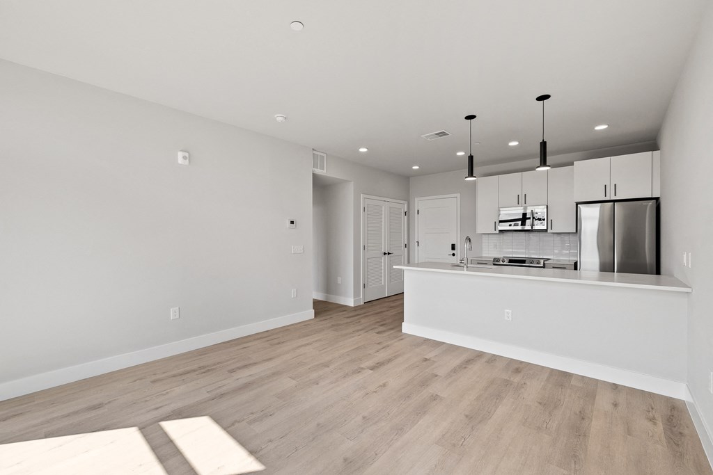 an open kitchen and living room with a large island and a refrigerator and microwave