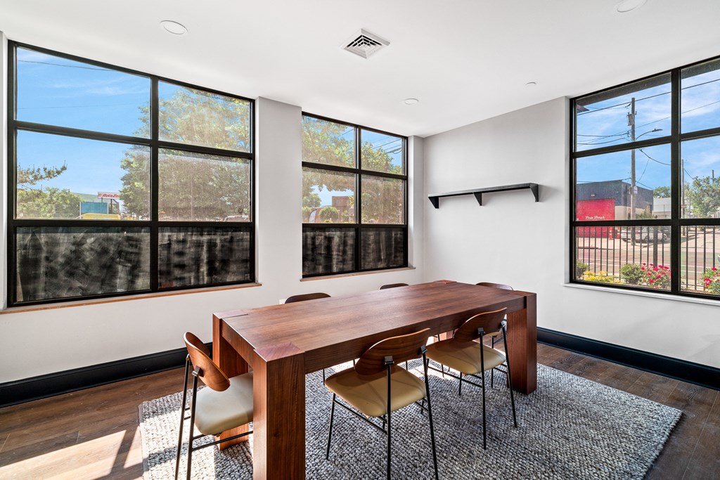 a dining room with a wooden table and chairs and large windows