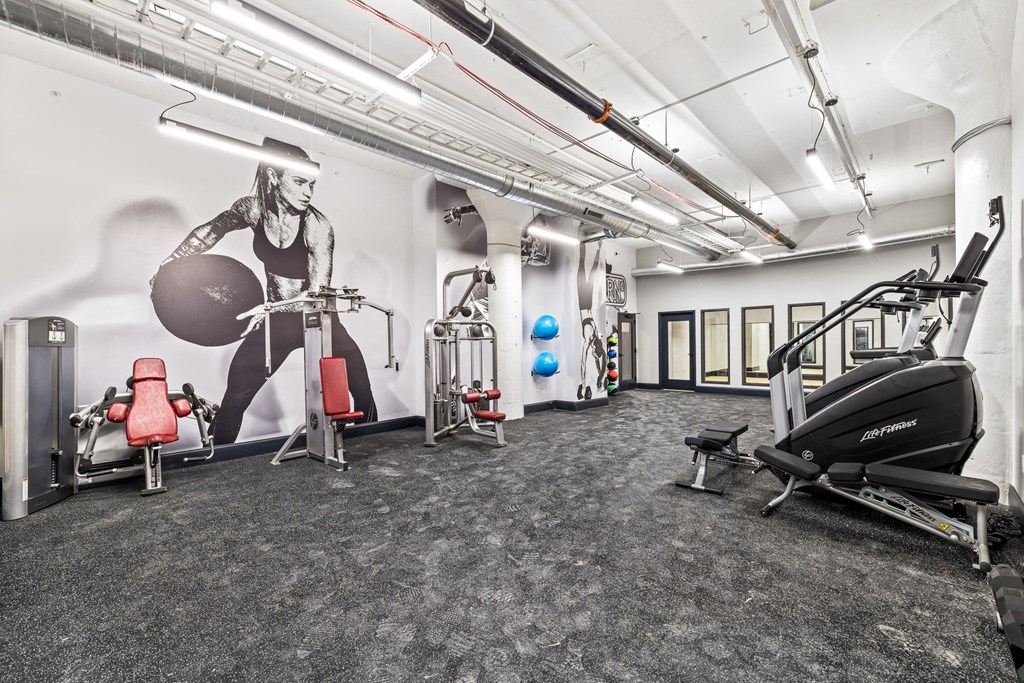 a gym with exercise equipment and a mural on the wall