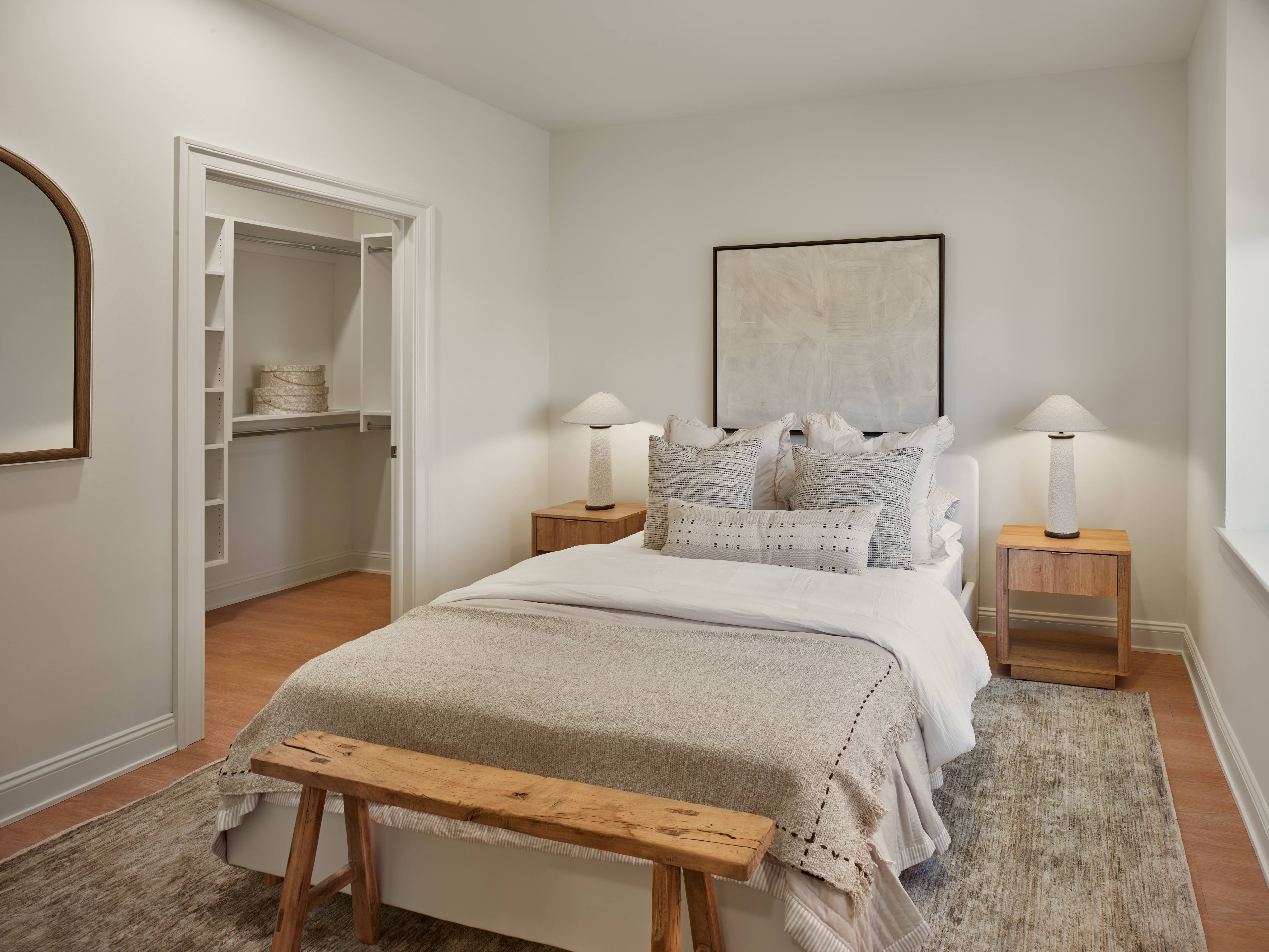 A bedroom with a large bed and a wooden bench.
