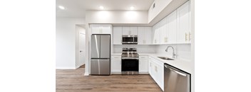 A modern kitchen with white cabinets and stainless steel appliances.