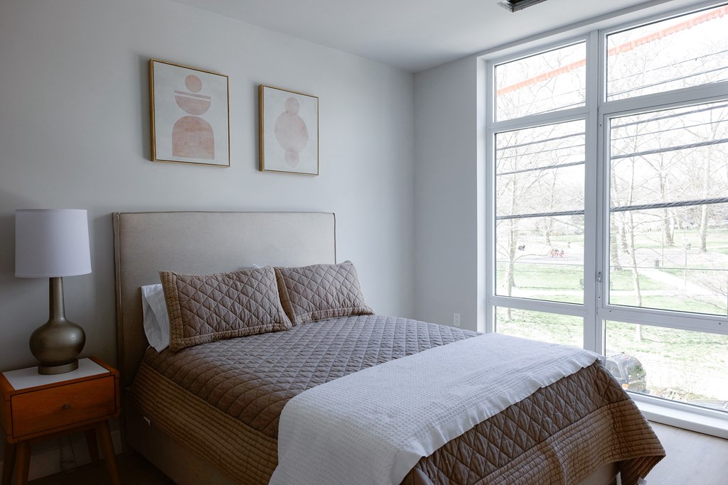 a bedroom with a bed and two large windows