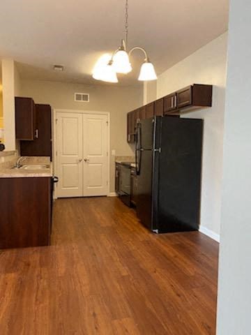 a kitchen with a black refrigerator and a wooden floor