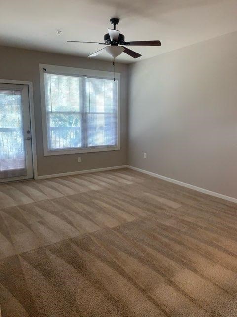 an empty living room with a ceiling fan and a window