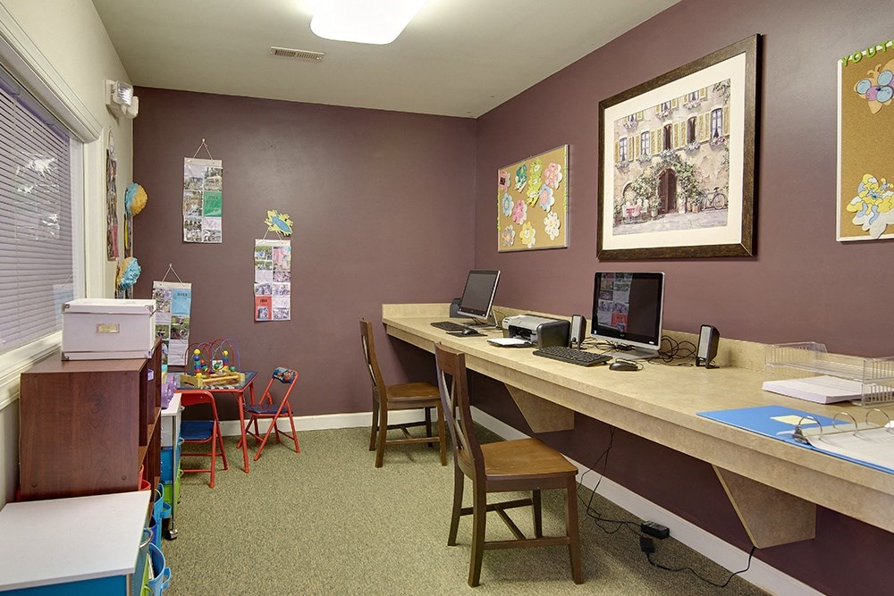 a classroom with a desk with a computer and chairs and a table with chairs