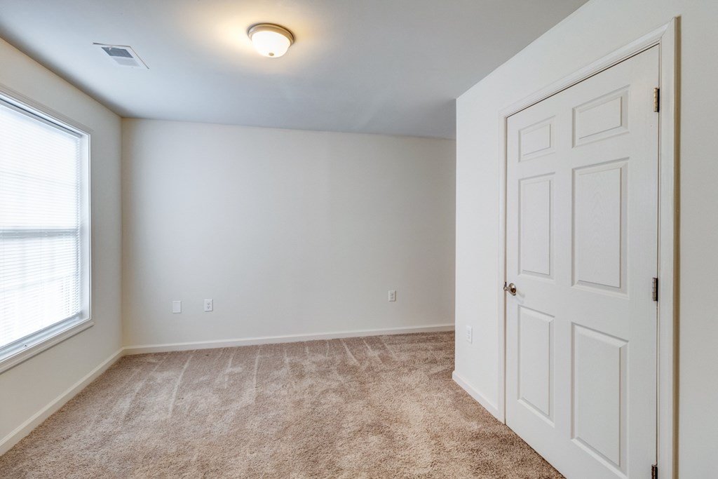 A room with a carpeted floor and a white door at Ada Park Apartments, Newport News, VA, 23601