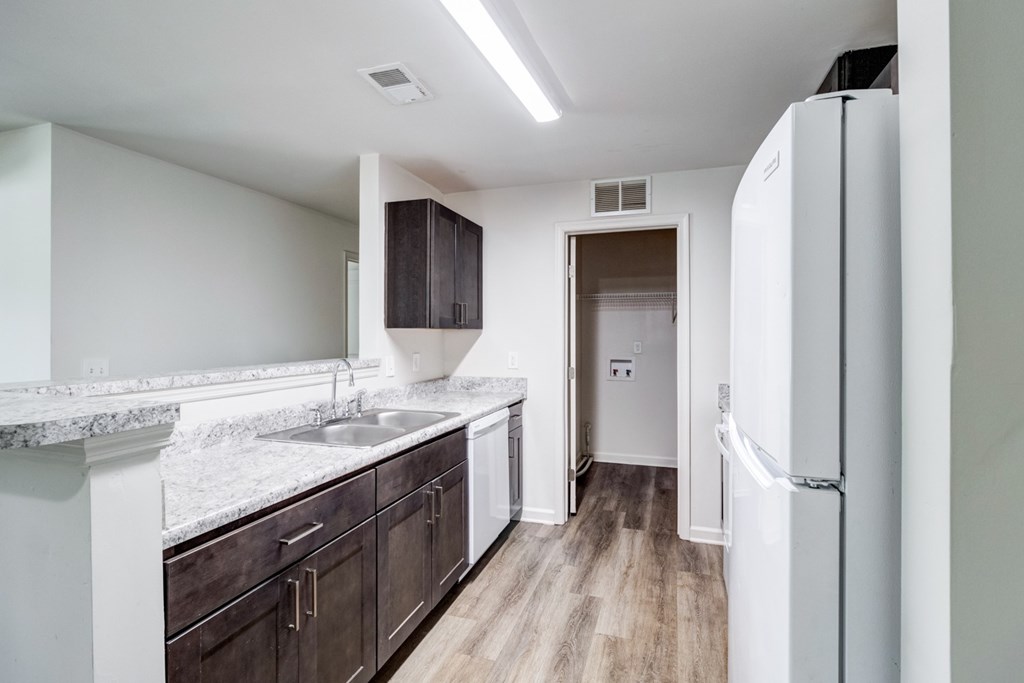 A kitchen with a white fridge and brown cabinets. at Ada Park Apartments, Newport News