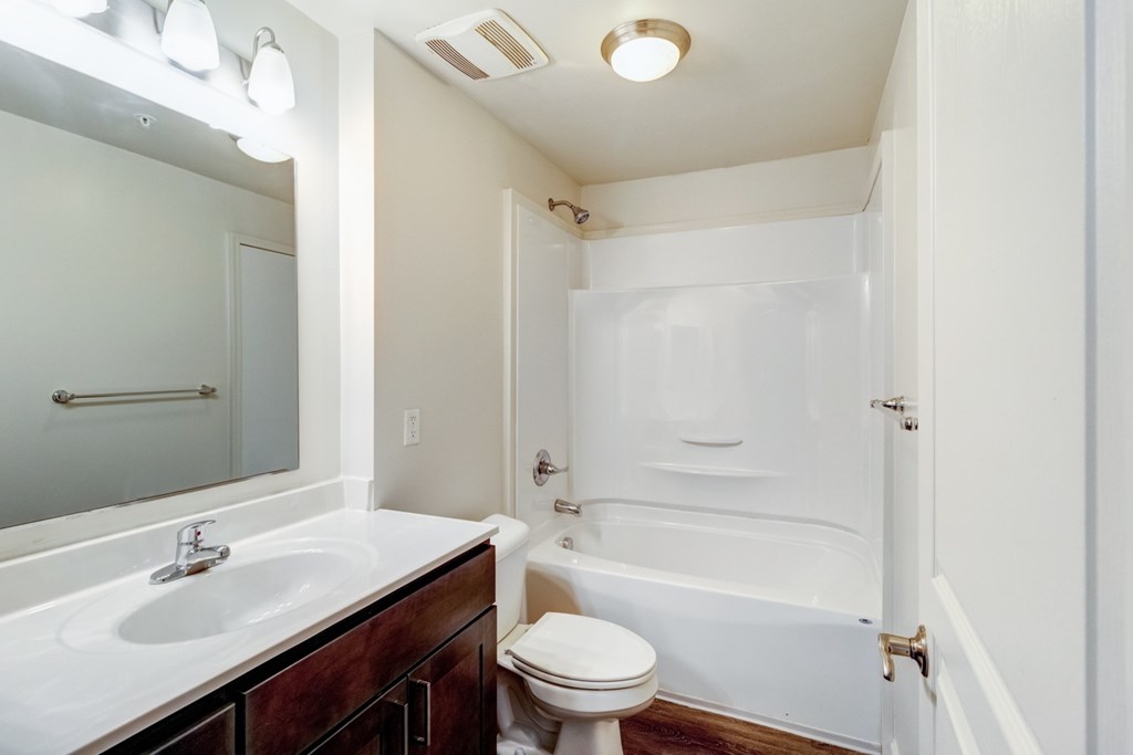 A white bathroom with a toilet, sink, and bathtub. at Ada Park Apartments, Newport News, VA