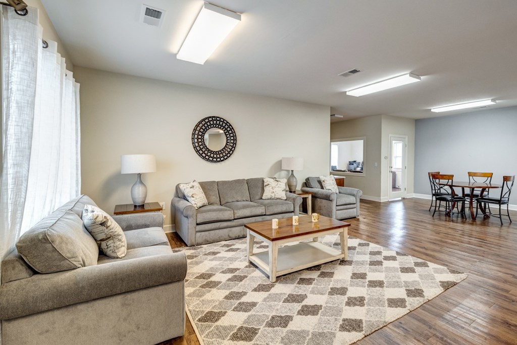 A living room with a couch, a coffee table, and a dining table. at Ada Park Apartments, Newport News, VA