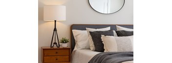 A bedroom with a bed, pillows, a lamp, and a mirror. at Anderson Center Apartments, Mullins