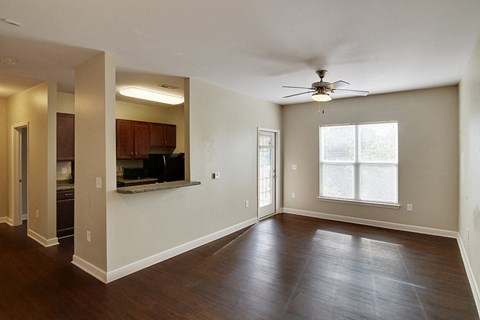 an empty living room with wood floors and a ceiling fan