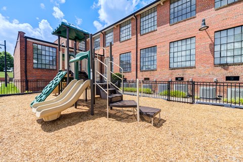 A playground with a green slide and a brown surface.