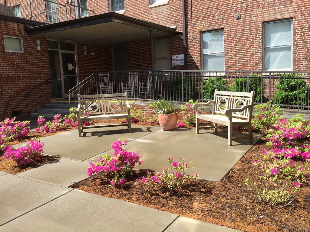 two benches in front of a brick building with flowers