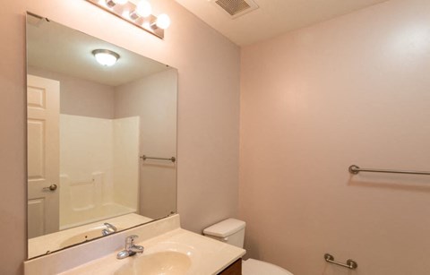 A bathroom with a sink, mirror, toilet and shower.