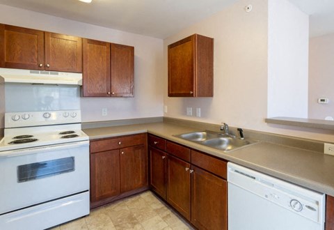 A kitchen with a white stove and wooden cabinets.
