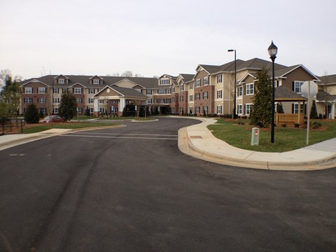 A street view of apartment buildings with a sidewalk and lamp post.